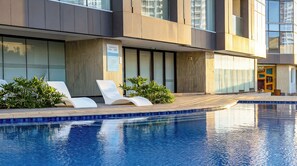 A modern building with a swimming pool, lounge chairs, and a clear view of the surrounding area. - Aeon Towers Private Residential Apartments I Next to Abreeza Ayala Malls I Prime Location l Fast Wifi l Free Pool I Managed by Bleuspace (Davao)