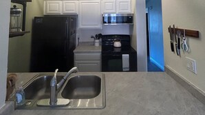 A compact kitchen with a built-in oven, a microwave, and a stainless steel sink.