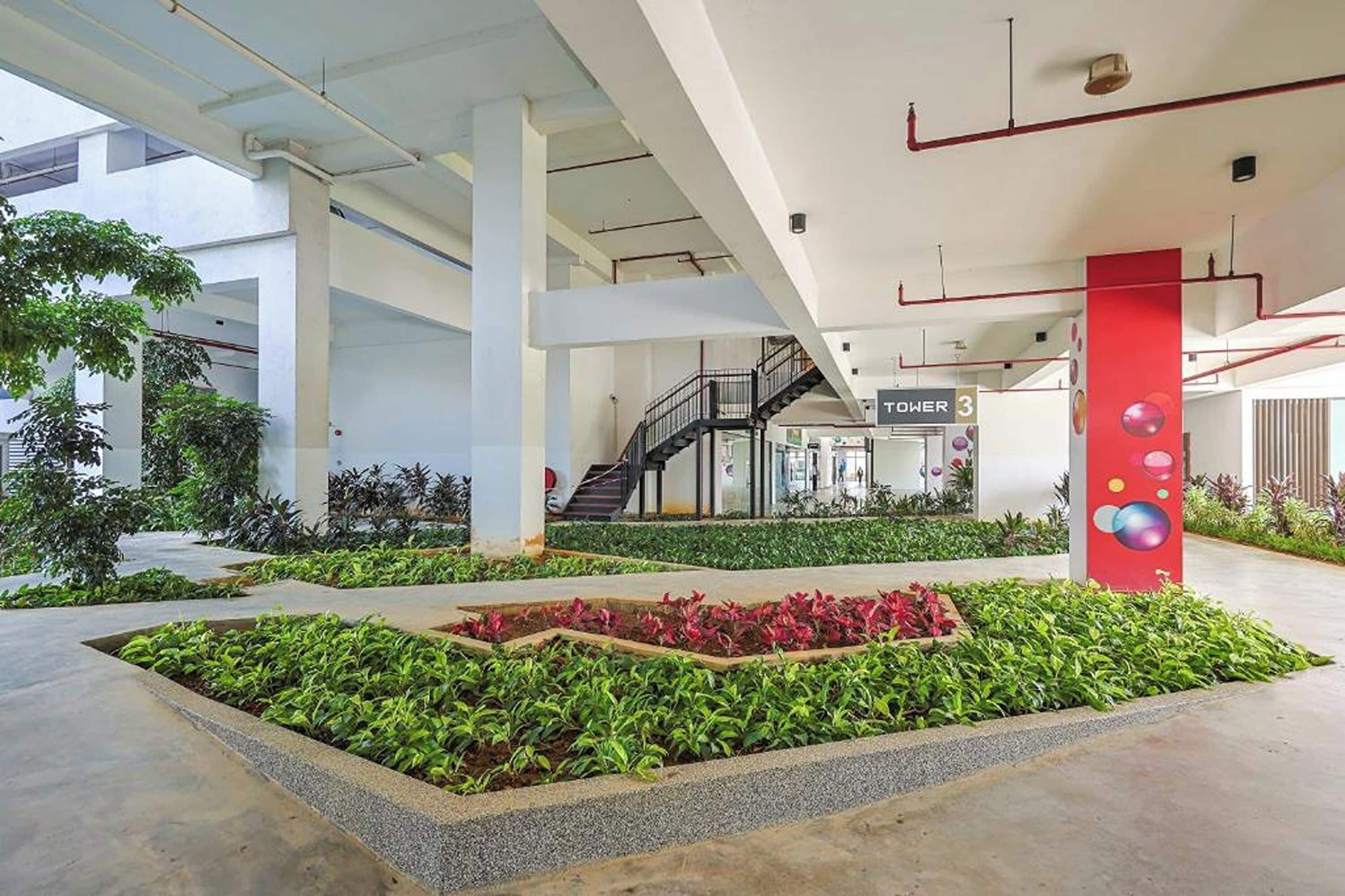 Un espacio interior amplio con un jardín central, una escalera y un letrero que indica 'TOUR 3'.