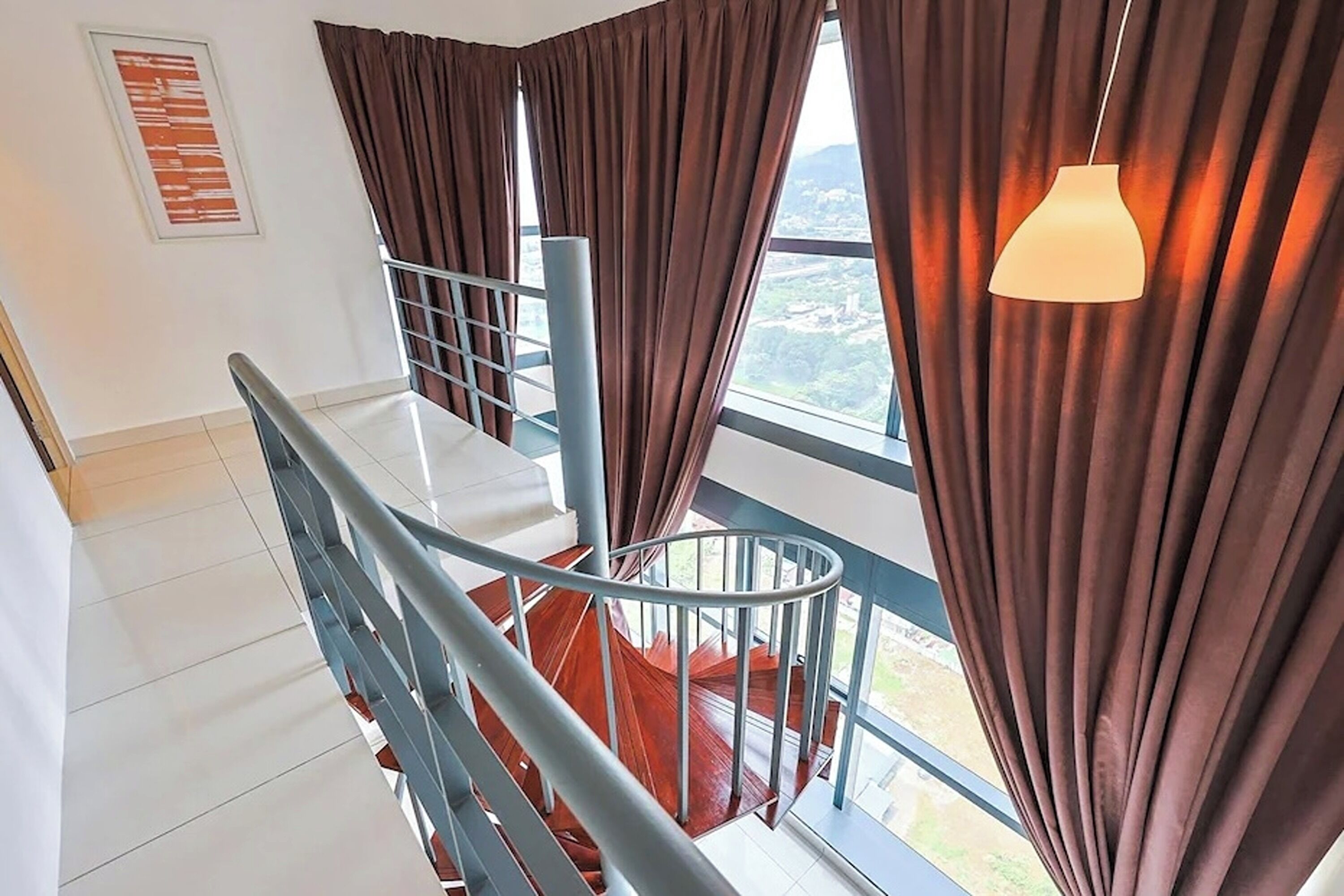 A staircase with metal railings, a view through large windows, and a hanging light fixture.