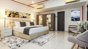 Un dormitorio moderno con una cama, mesitas de noche, un cuadro abstracto grande, un armario y una zona de estar con una silla y un florero.