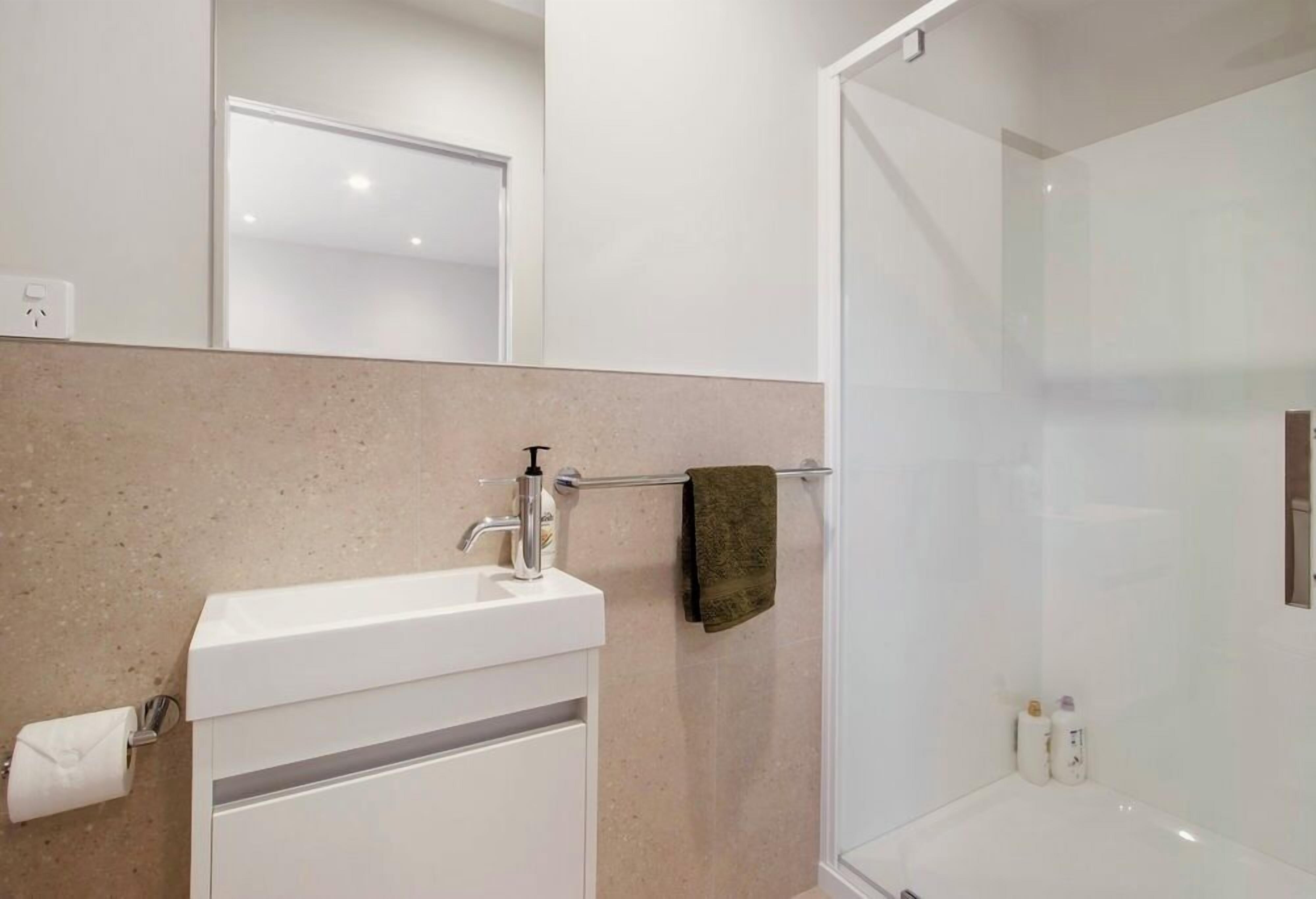 Une salle de bain avec un lavabo blanc, un porte-serviettes et une cabine de douche en verre.