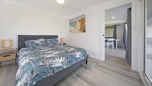 A bedroom with a bed, a ceiling fan, a painting, a nightstand, and a view of a dining area. - Absolute Waterfront Bliss – Pet Friendly, Seperate living areas, Family Shack. (Pellaring Flat)