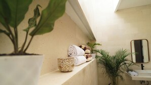 Een badkamer met een inbouwkastje met handdoeken en een potplant.
