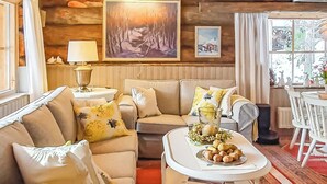 Un salón acogedor con un conjunto de sofás, una mesa de centro con objetos decorativos, una lámpara y cuadros en la pared.