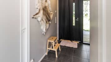 A hallway with a fur coat on the wall, a wooden stool, and a black door.