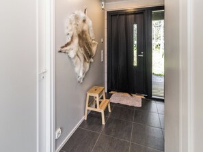 A hallway with a fur coat on the wall, a wooden stool, and a black door.