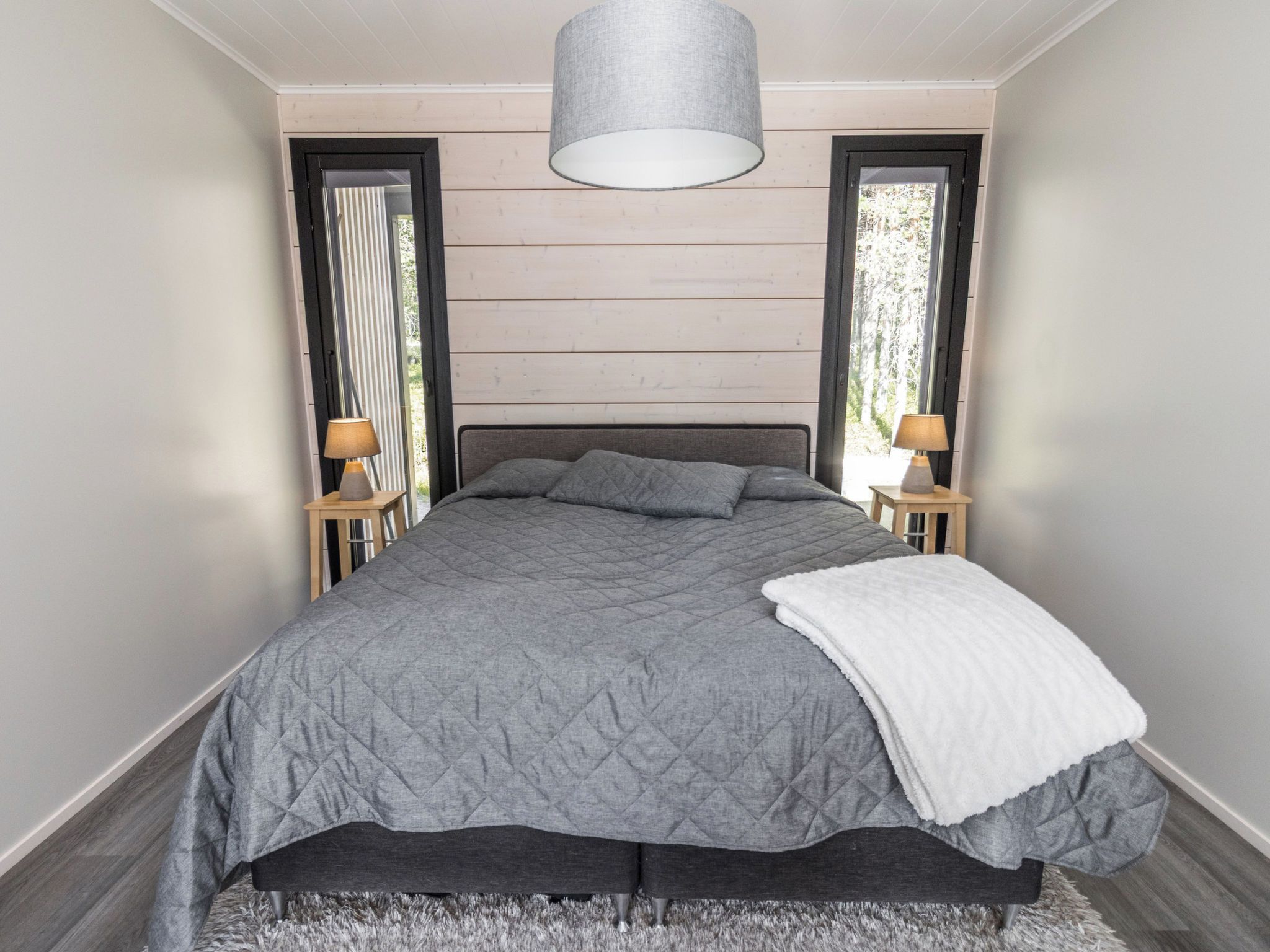 Een moderne slaapkamer met een groot bed, twee bedlampen en uitzicht door het raam.