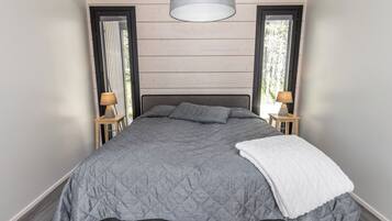 Een moderne slaapkamer met een groot bed, twee bedlampen en uitzicht door het raam.
