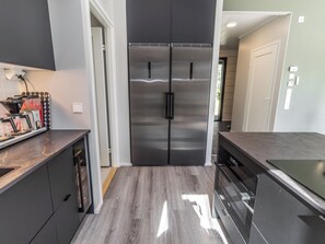 A modern kitchen with a stainless steel double-door refrigerator, a built-in dishwasher, and a countertop with a coffee machine.