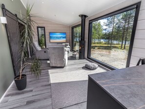 A modern living room with a large window, a fireplace, and a view of a lake.