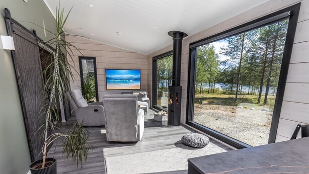 A modern living room with a fireplace, comfortable seating, and a large window offering a view of the outdoors.