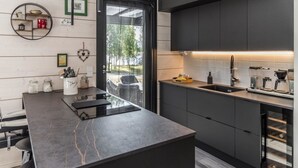 A modern kitchen with a dark countertop, built-in cabinets, a coffee machine, and a view of the outdoors.