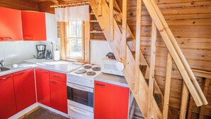 Una cocina con armarios rojos, una estufa blanca y un techo de madera.