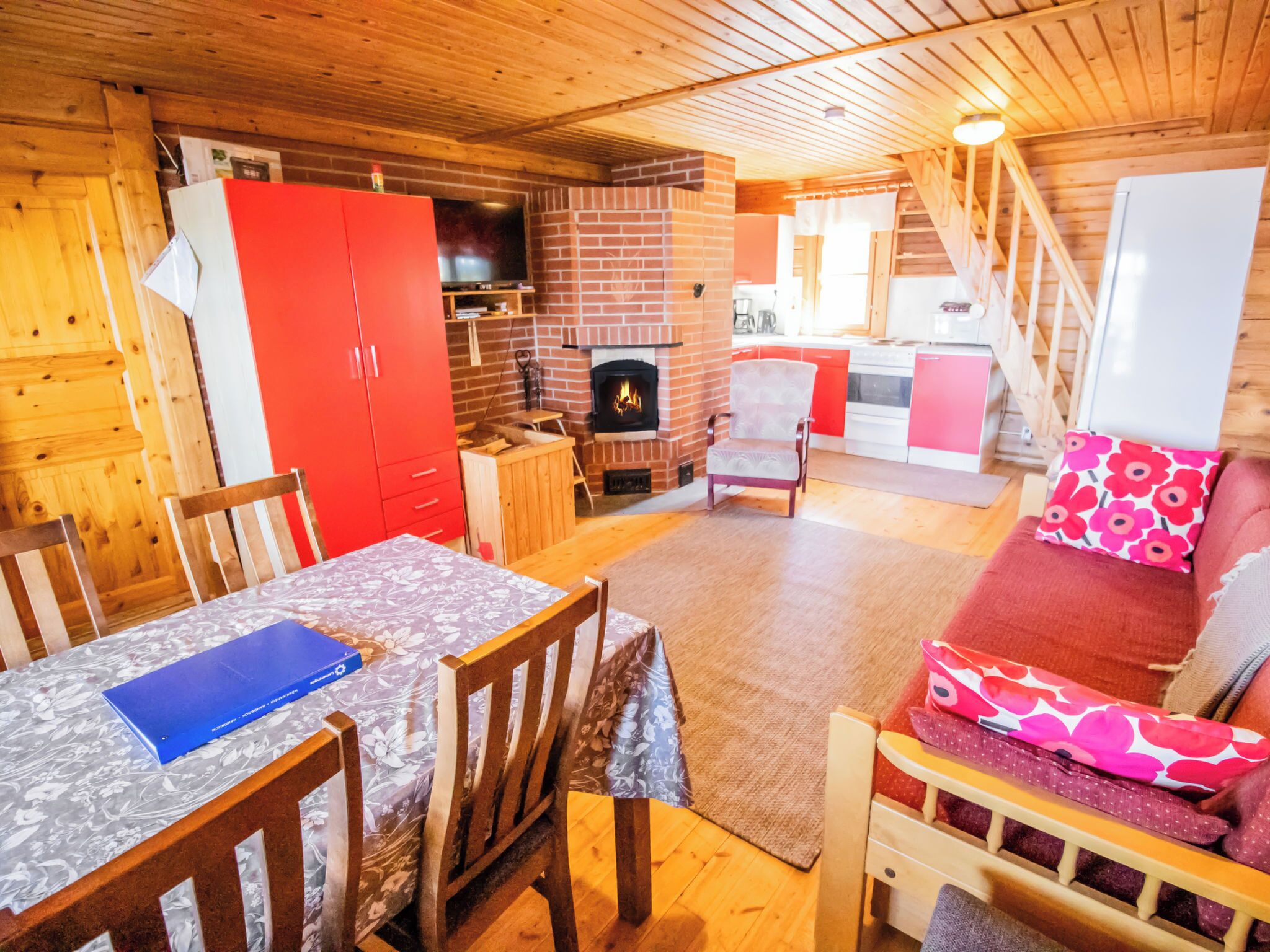 A cozy cabin interior with a dining area, a fireplace, and a kitchen.