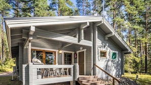 En stuga med en veranda, trätrappor och utsikt över den omgivande skogen.