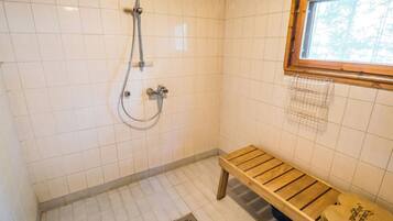 A small, tiled shower area with a wooden bench and a window.