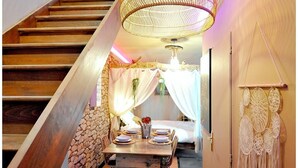 A staircase leading to a dining area with a table set for four, a hanging light fixture, and a wall with dreamcatchers.