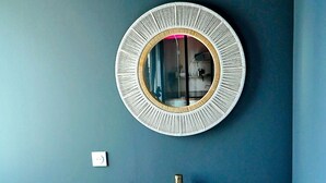 A bathroom with a round mirror, a stone sink, and a wooden vanity.