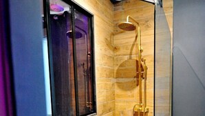A modern shower area with a glass door, wooden panel walls, and a visible window.
