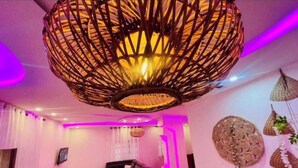A modern interior with a large woven light fixture, a sectional sofa, and decorative wall art. - Modern vacation apartment with washing machine and king-size bed (Lomé kpogan)