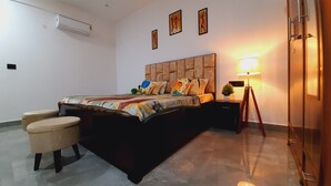 A bedroom with a bed, bedside tables, a lamp, and a potted plant. - Cozy and Tranquil Nest ( With wifi and Homely Care ) (Greater Noida)
