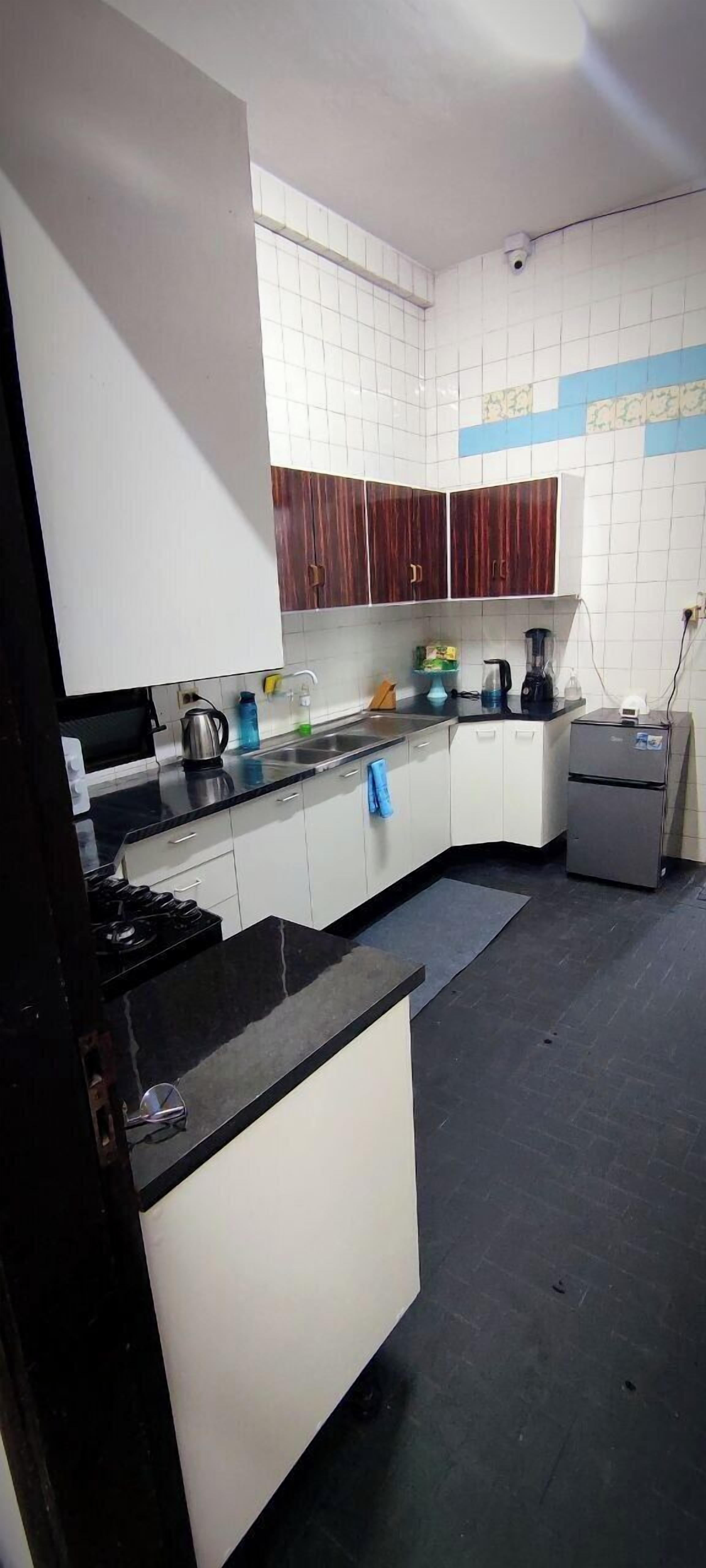 A kitchen with white cabinets, a black countertop, a stove, a sink, and a refrigerator.