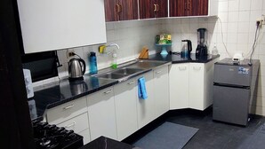 A kitchen with white cabinets, a black countertop, a stove, a sink, and a refrigerator. - Cuba linda  (Asunción)