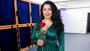 A woman in a green dress holding a rose in a room with blue curtains and a blue carpet. - Cuba linda  (Asunción)