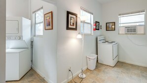 A compact kitchen with a washer and dryer, a stove, and a trash can. - Walk to King Street Eats! Condo in Jacksonville (Jacksonville)