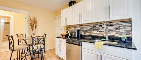A modern kitchen with white cabinets, a dishwasher, and a tiled backsplash.