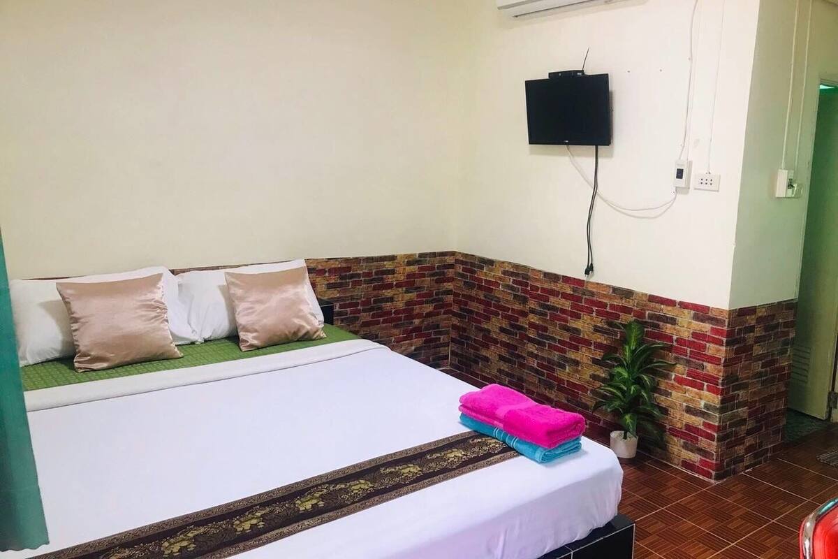 Ein Hotelzimmer mit einem Bett, einem an der Wand montierten Flachbildfernseher und einer Wand mit Ziegelsteinverkleidung.