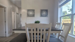 A dining area with a table and chairs, a hanging light fixture, and two wall-mounted artworks.