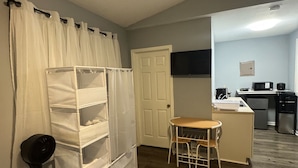 A compact living space with a kitchenette, a small dining area, and a storage unit against the wall.