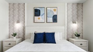 A bedroom with a large bed, two bedside tables, a headboard, and abstract wall art. - Elegant 2BR in Storey Lake, Top Location (Kissimmee)