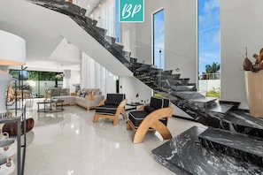 A modern interior with a staircase, seating area, and large windows.
