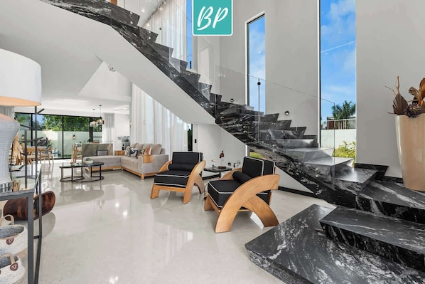 A modern interior with a staircase, seating area, and large windows.