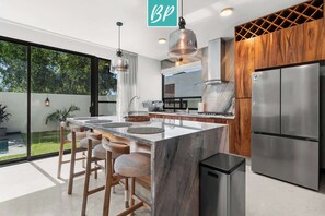 A modern kitchen with a large island, stainless steel appliances, and a view of the outdoors. - 4BR w/ Private Heated Pool & Beach Club - Villa 2 (Cruz de Huanacaxtle)
