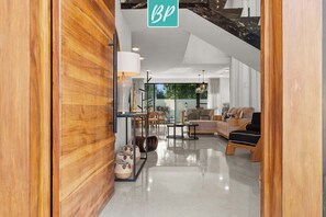 A modern interior with a wooden accent wall, a seating area with a sofa and chairs, and a staircase with a 'BP' sign.