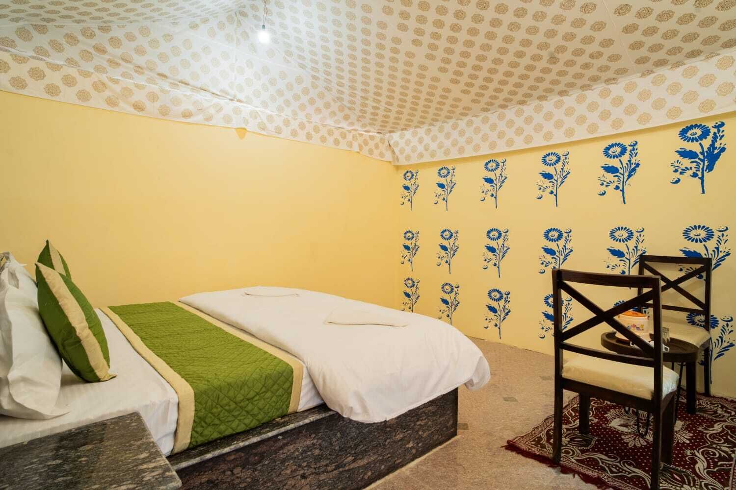 Una habitación con cama, una silla, un papel tapiz estampado y un techo con diseño de lunares.