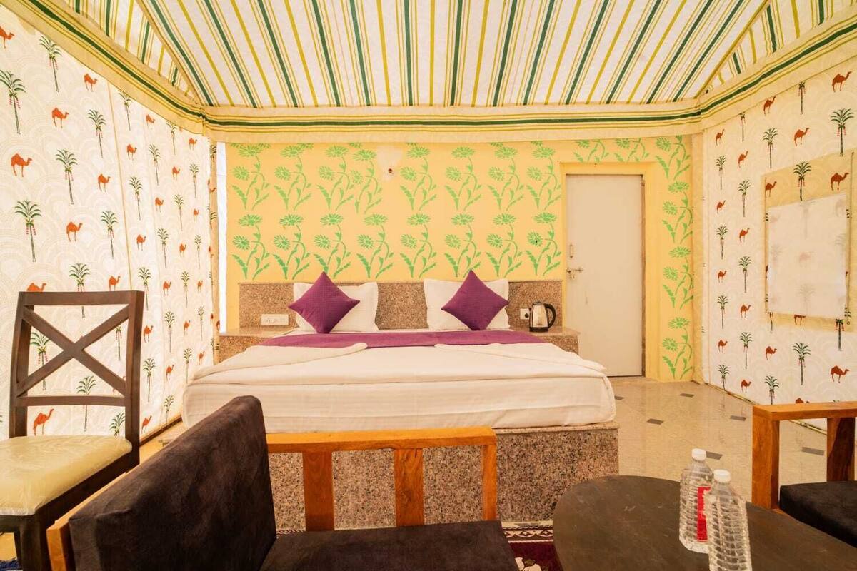 Una habitación con cama, dos sillas, una mesa y una botella de agua.