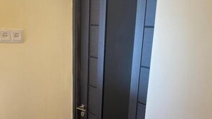 A dark-colored door with a number '1' above it, a door handle, and a light switch on the wall to the left.