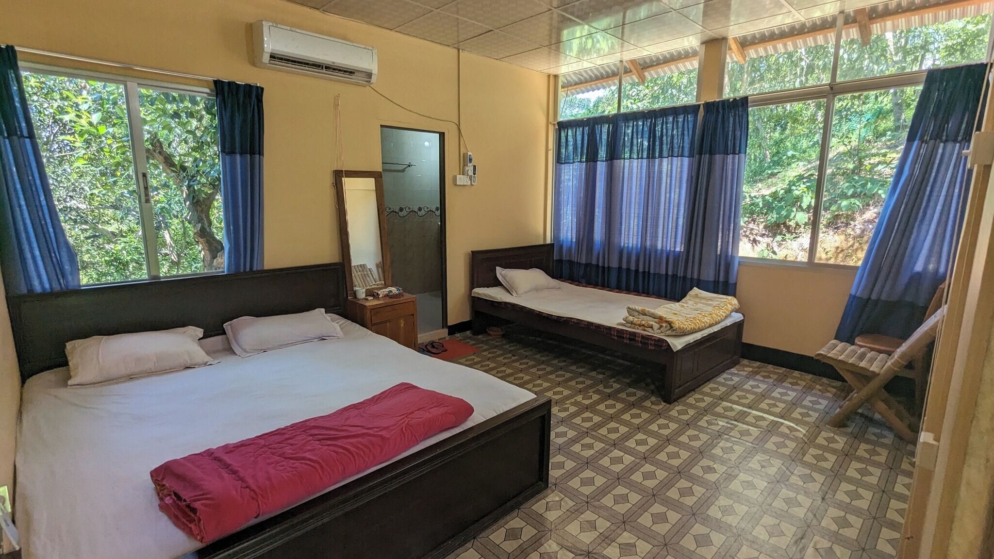 Quarto com duas camas, um espelho e uma janela com cortinas.