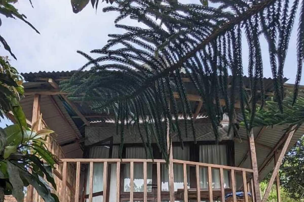 Una casa de dos pisos con balcón, puertas de madera y techo de paja.