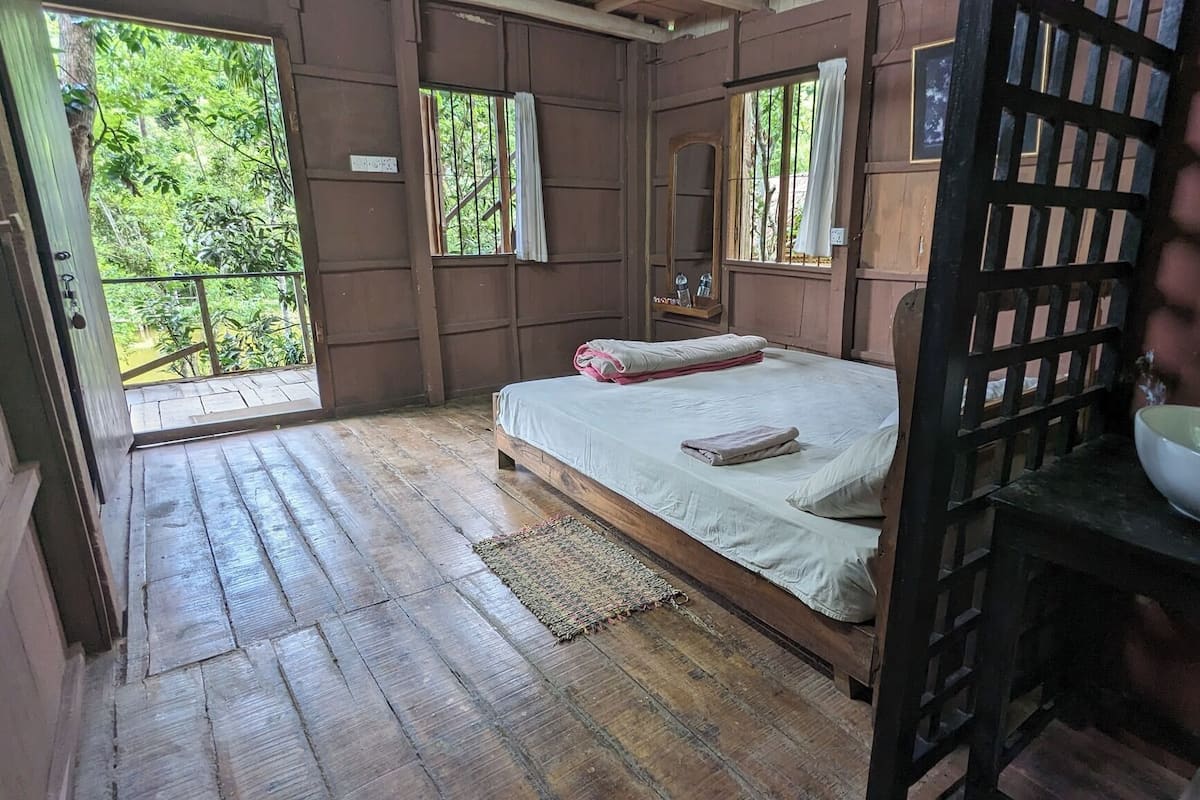 Una habitación de madera con una cama, una ventana y un lavamanos.