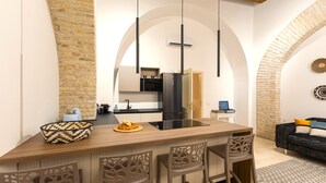 Una cuina moderna amb una illa central, tamboretes de bar i llums penjants.