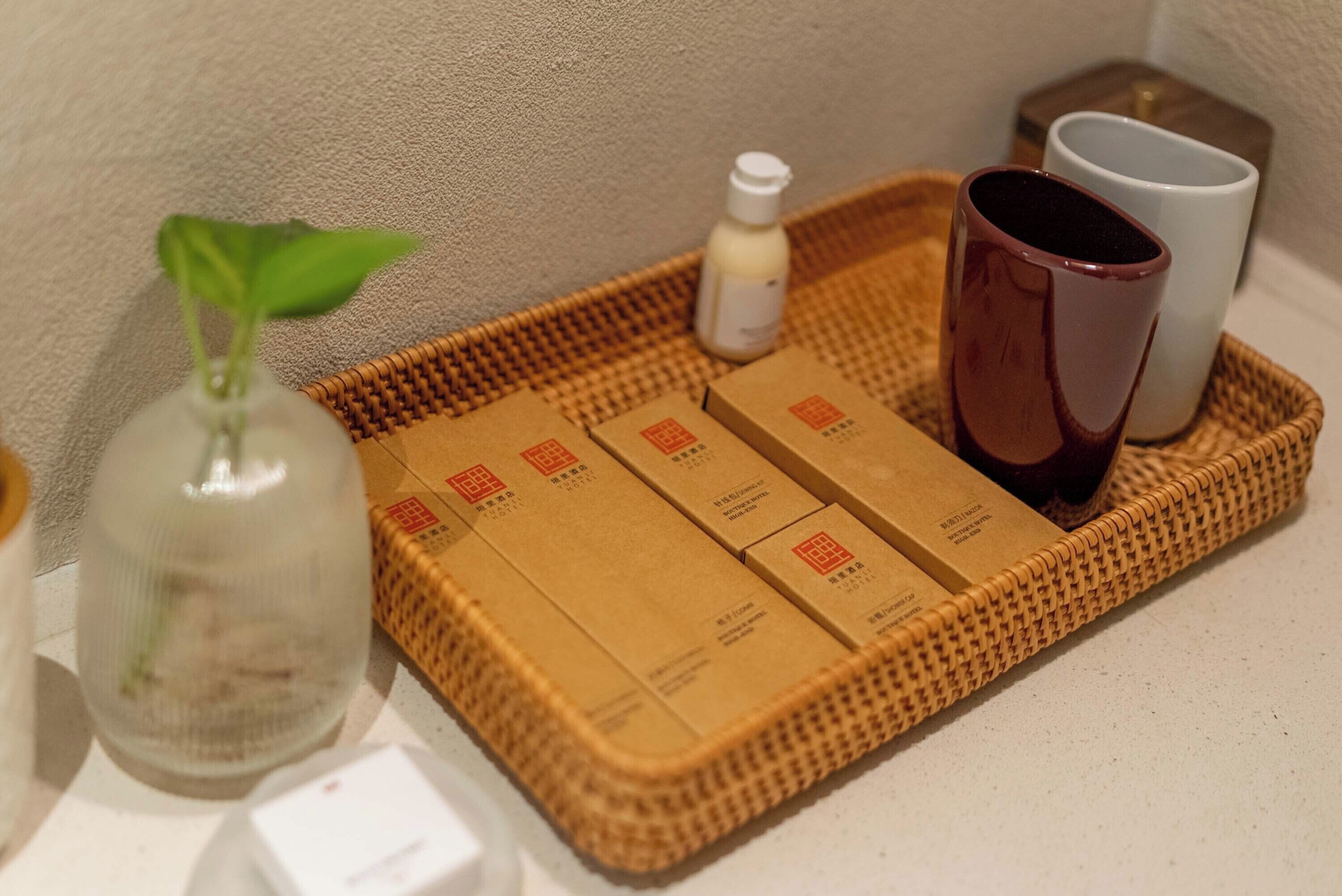 A tray with toiletries, a potted plant, and two cups.