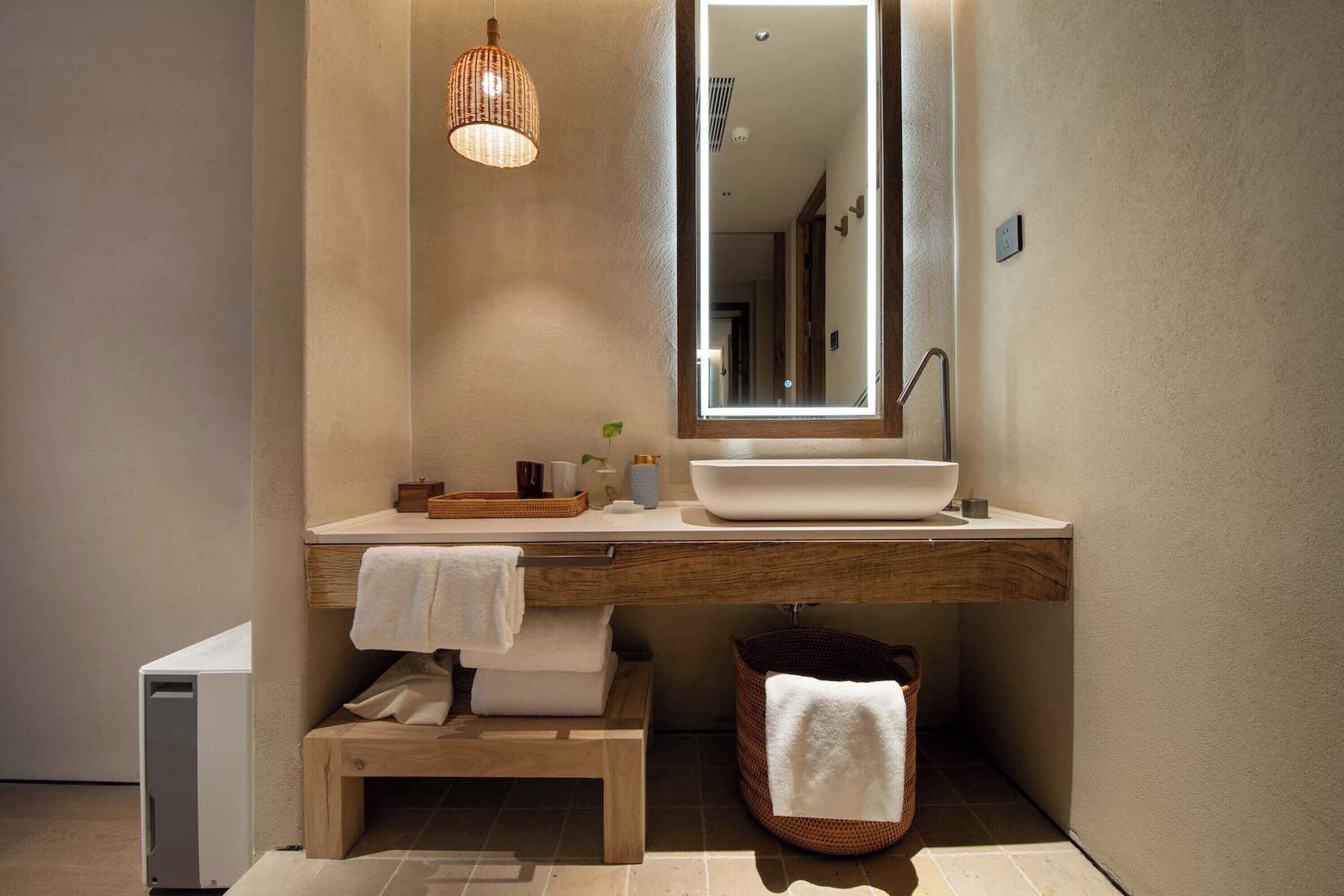 A modern bathroom with a large mirror, a vessel sink, and a wooden vanity.