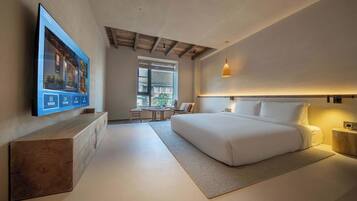 A modern bedroom with a large bed, a TV mounted on the wall, and a wooden bench.
