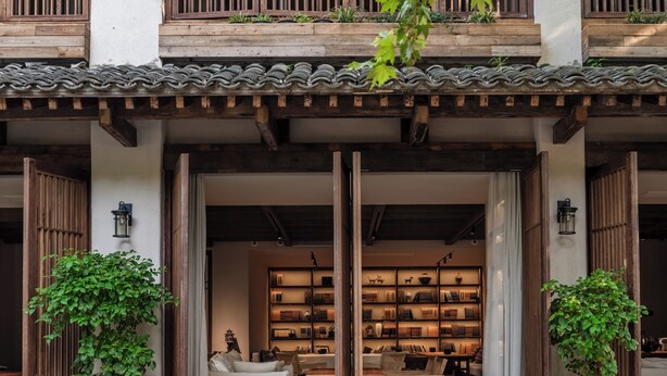 Un bâtiment traditionnel avec un toit en tuiles, des poutres en bois et un espace central ouvert où se trouvent des étagères à livres.